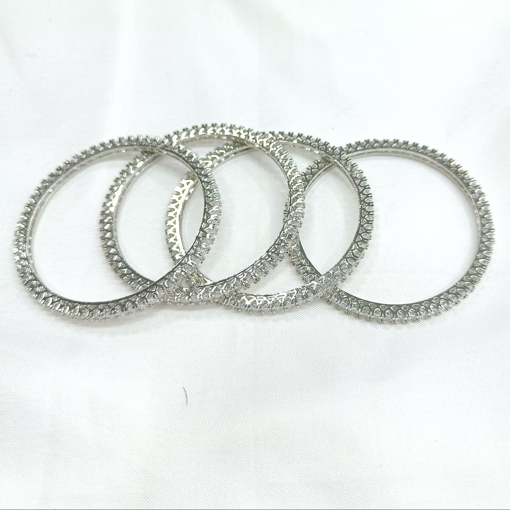 Set of silver american diamond bangles on a white background