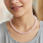 Woman wearing a pink beaded necklace against a blurred background
