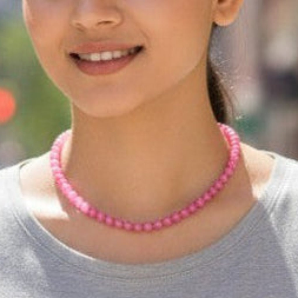 Woman wearing a pink necklace on a city street