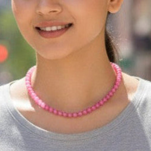 Woman wearing a pink necklace on a city street