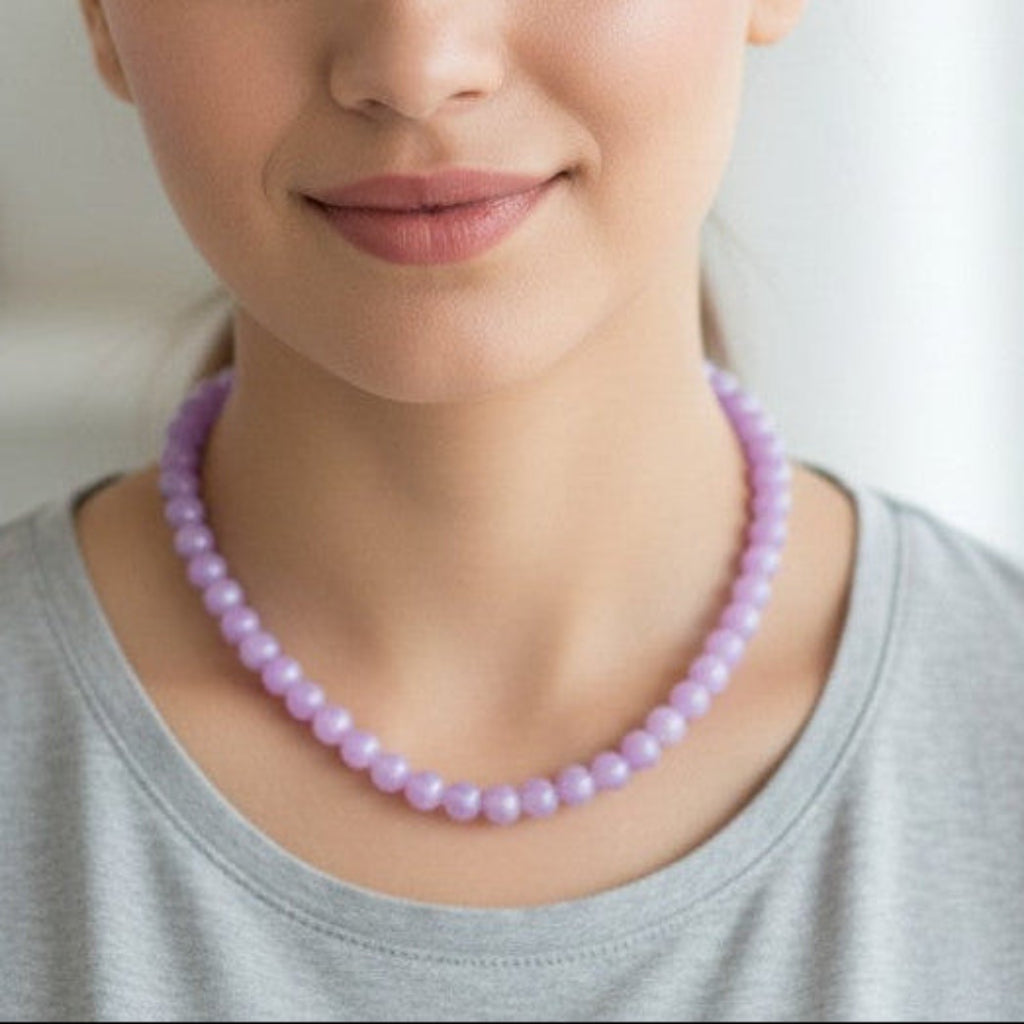 Woman wearing a purple beaded necklace against a neutral background