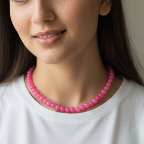 Woman wearing a pink beaded necklace against a neutral background