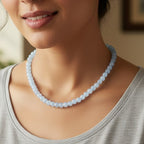 Woman wearing a light blue beaded necklace indoors
