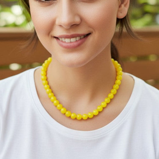Woman wearing a yellow beaded necklace in an outdoor setting