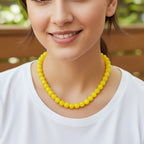 Woman wearing a yellow beaded necklace in an outdoor setting