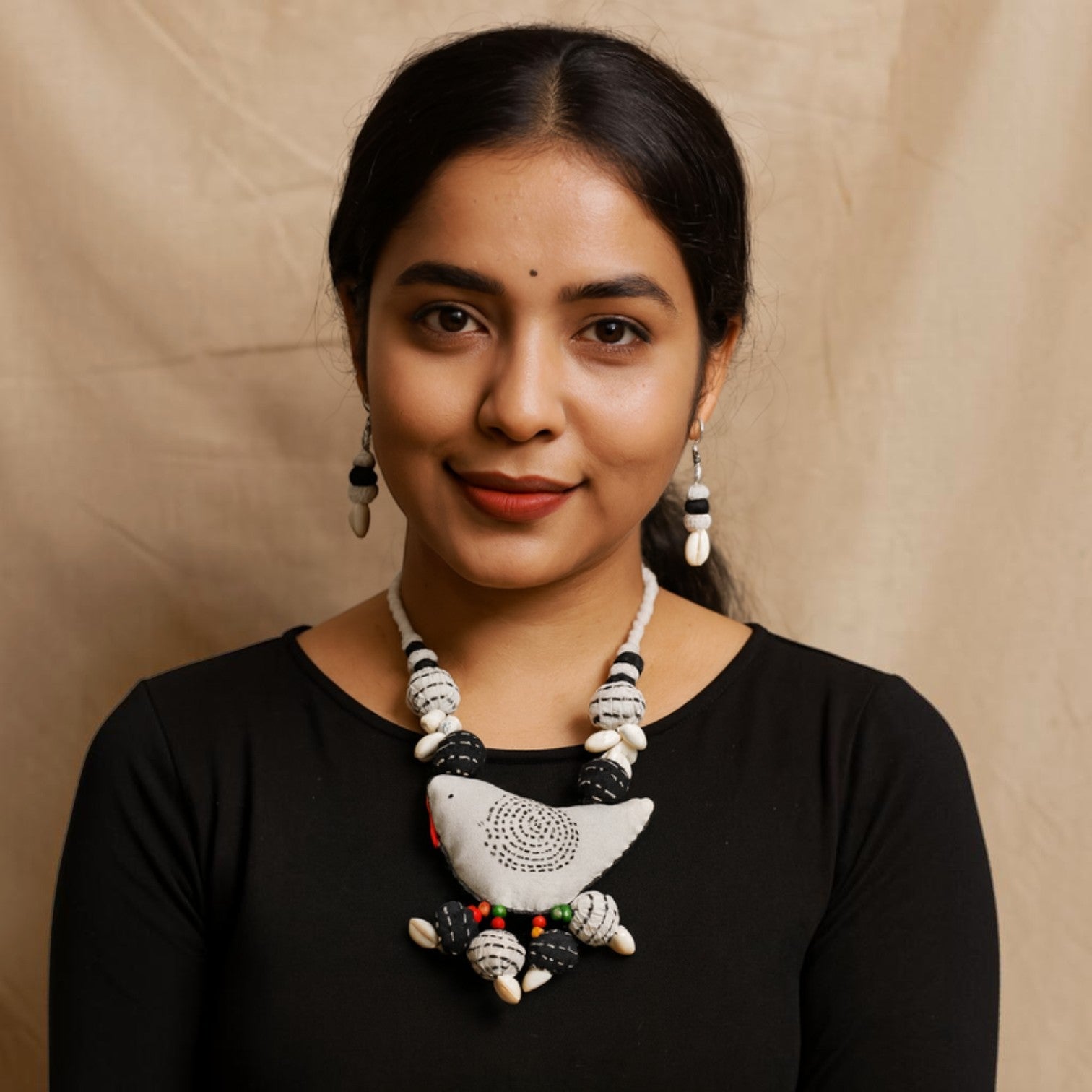 JewelOn fabric necklace with a bird pendant, black and white beads, and shell accents. Matching earrings.
