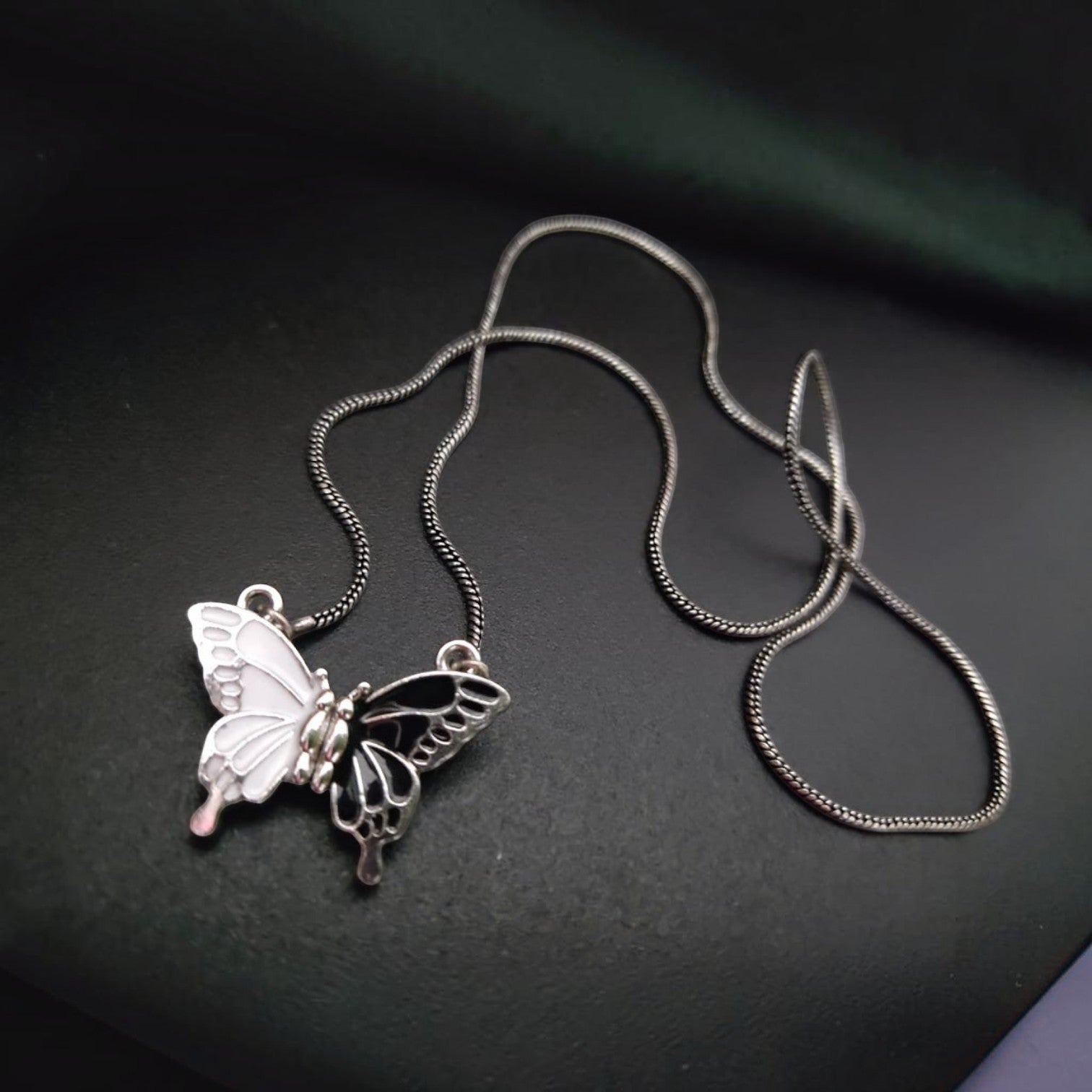 Jewelon magnetic butterfly pendant necklace with a silver chain. Half white, half black enamel.
