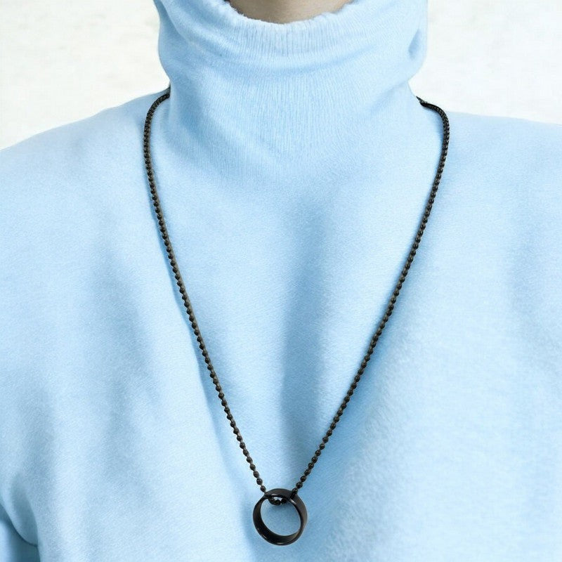 Jewelon men's minimalist ring pendant necklace on a dark ball chain, worn over a light blue turtleneck.