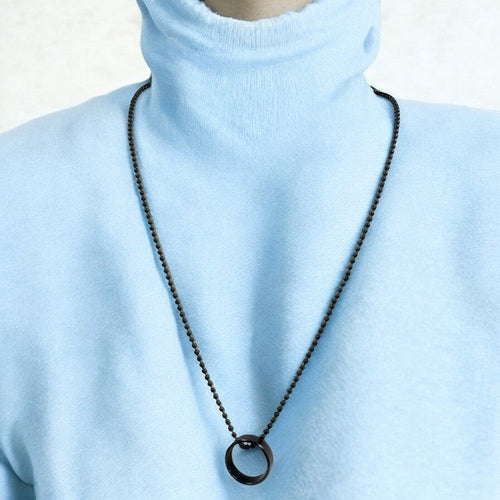 Jewelon men's minimalist ring pendant necklace on a dark ball chain, worn over a light blue turtleneck.