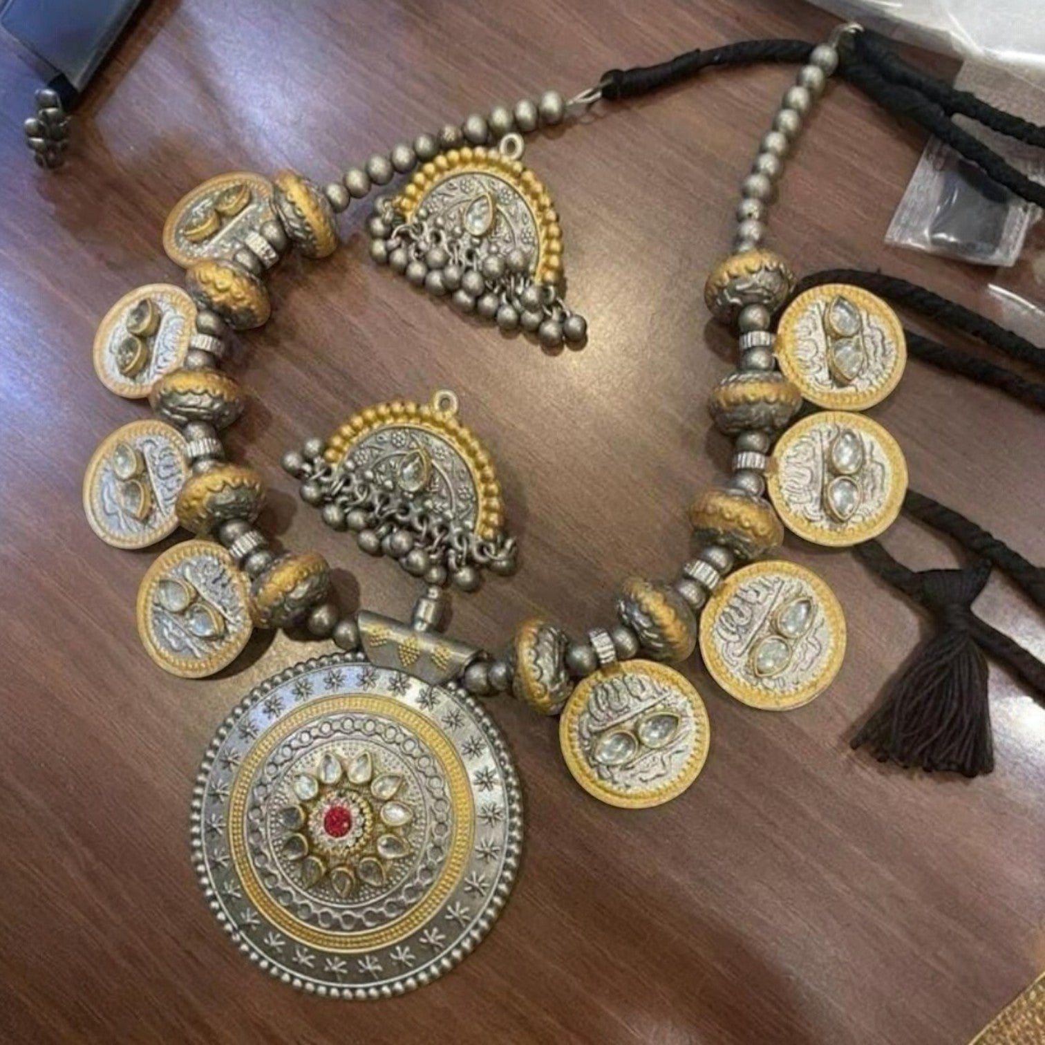 JewelOn two-tone oxidised necklace and jhumka earrings set with intricate coin details and a central red stone pendant.