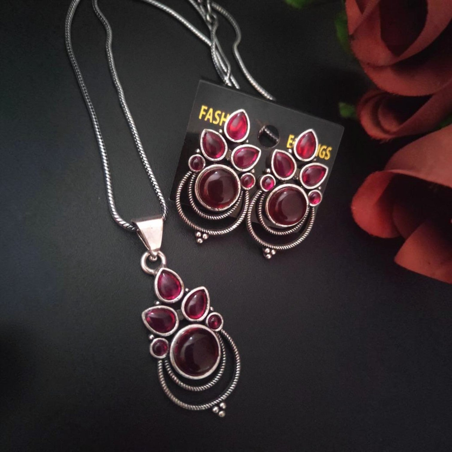 JewelOn oxidised silver necklace and earrings set with deep red stones and intricate detailing.