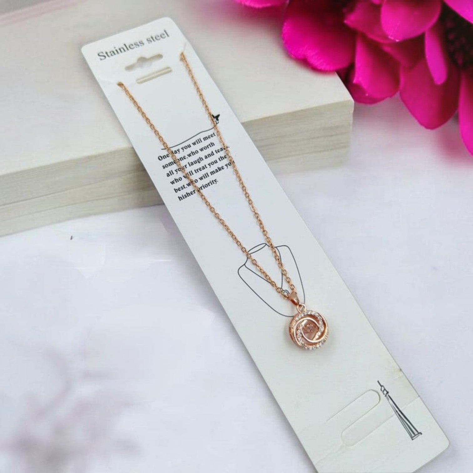 JewelOn rose gold pendant necklace with a circular, swirling design encrusted with small clear stones.