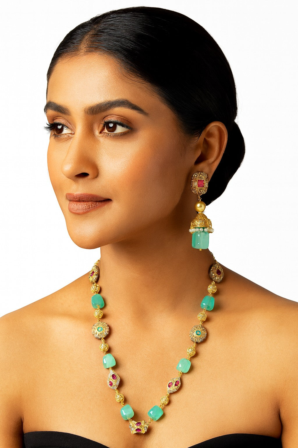 JewelOn gold-tone necklace and jhumka earrings with green stones and ruby accents. Model wears the jewellery set.