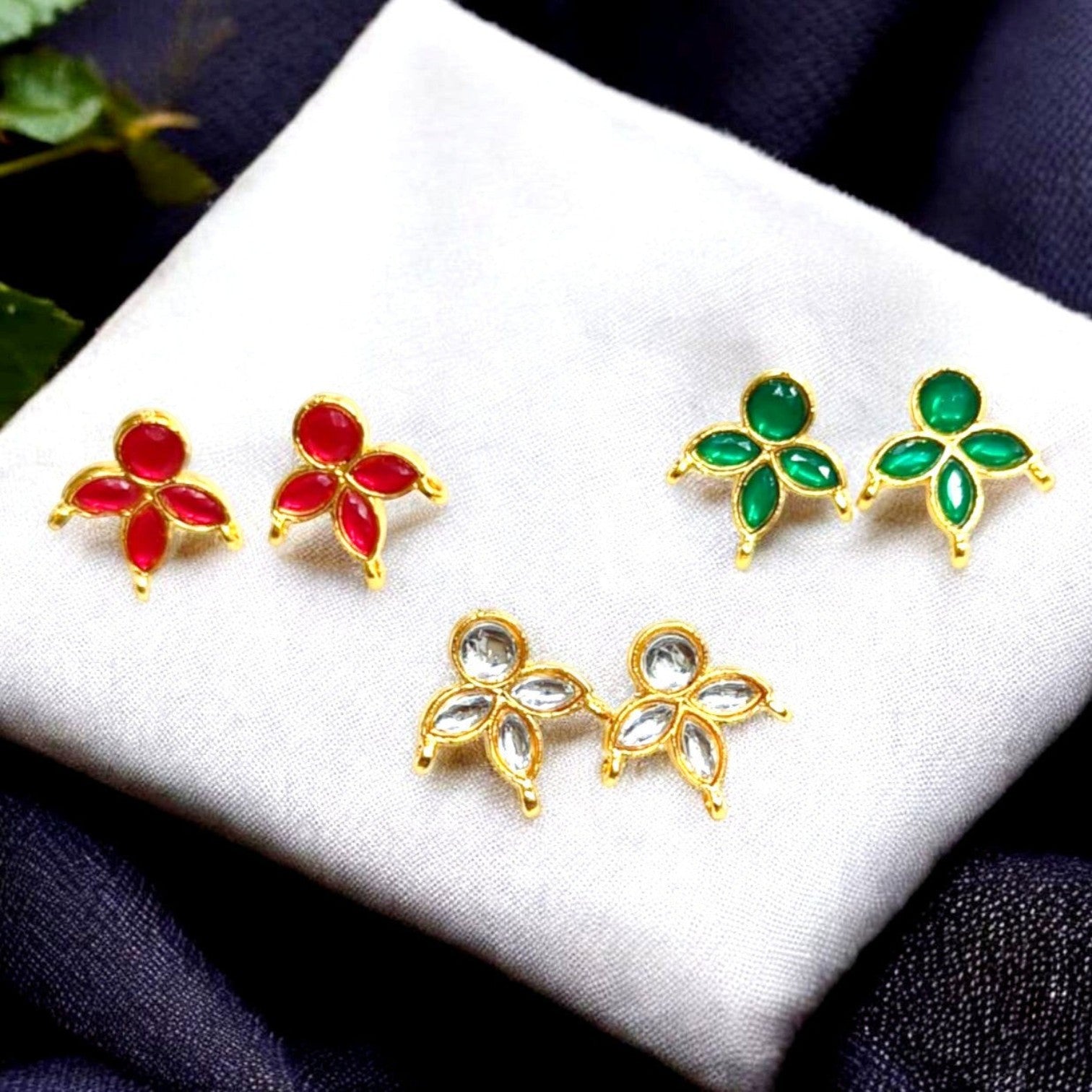 JewelOnHere Royal Presence Kundan Earring Combo: 3 pairs of gold-tone stud earrings with red, green, and clear kundan stones in a floral design.