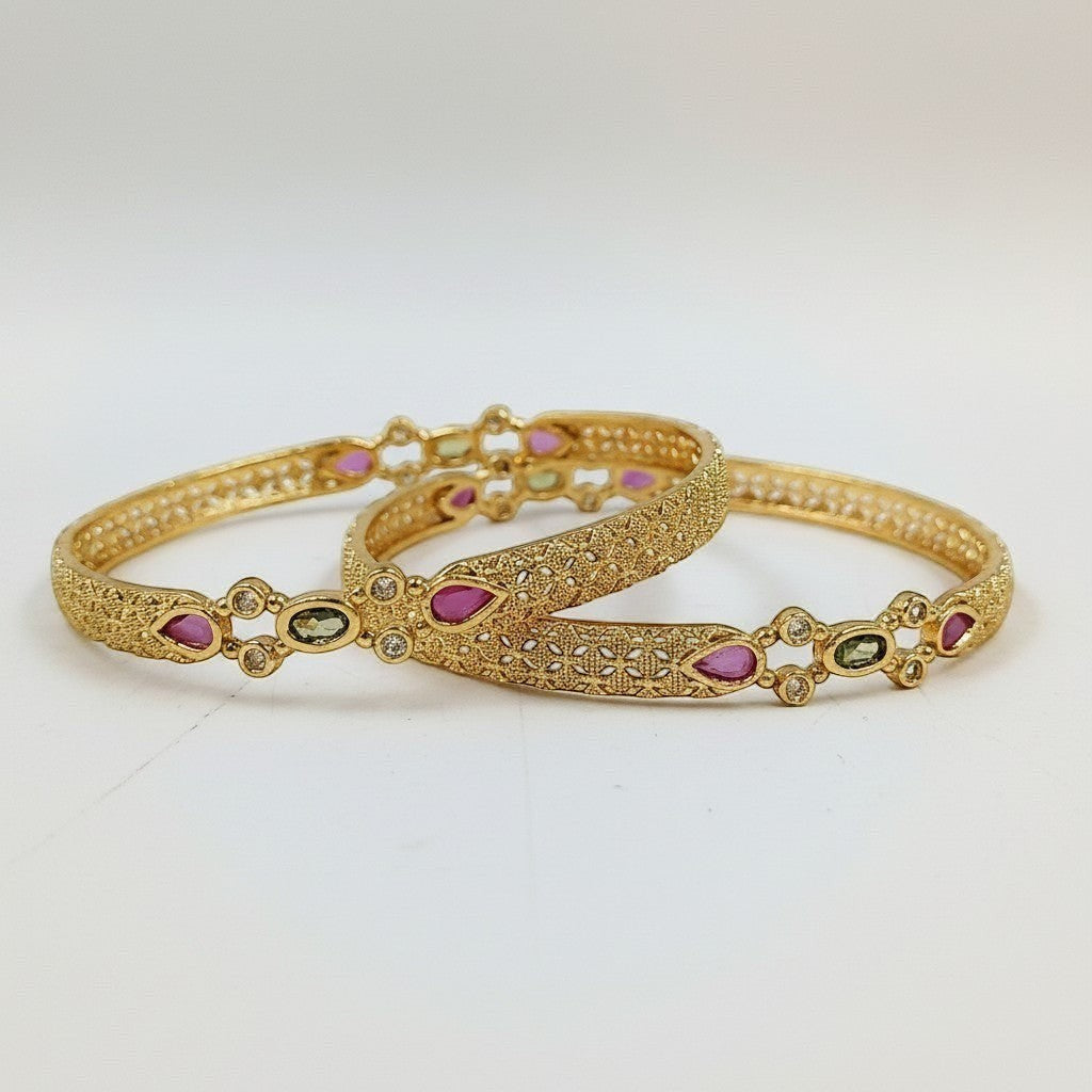 JewelOn Lumière gold plated bangles set for women, featuring intricate filigree design with pink and green teardrop stones and small clear crystals.