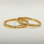 JewelOn gold plated bangles set with intricate detailing and small square cubic zirconia and ruby accents.
