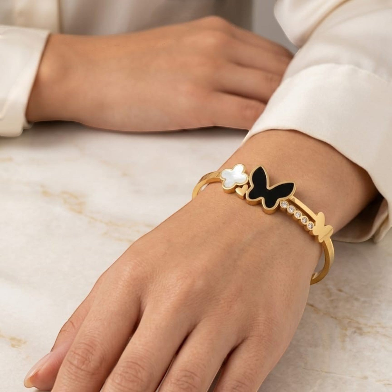 JewelOnHere gold-tone stainless steel cuff bracelet with black enamel butterfly, white clover charm, and cubic zirconia.